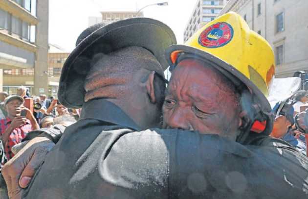 A firefighter is comforted at the wreathlaying ceremony for the three firefighters who died