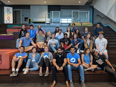 A bunch of students sitting down and smiling at the camera