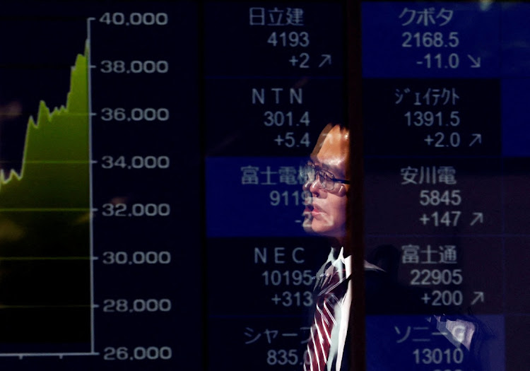 A passerby is reflected on an electronic screen displaying a graph showing recent Japan's Nikkei share average movements and stock prices as the share average hits a record high in Tokyo, Japan, on February 26 2024. Picture: REUTERS/ISSEI KATO