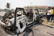 People inspect a burned police car, after two groups of Muslims clashed outside Martyrs Stadium in Kinshasa, Democratic Republic of Congo May 13, 2021. 