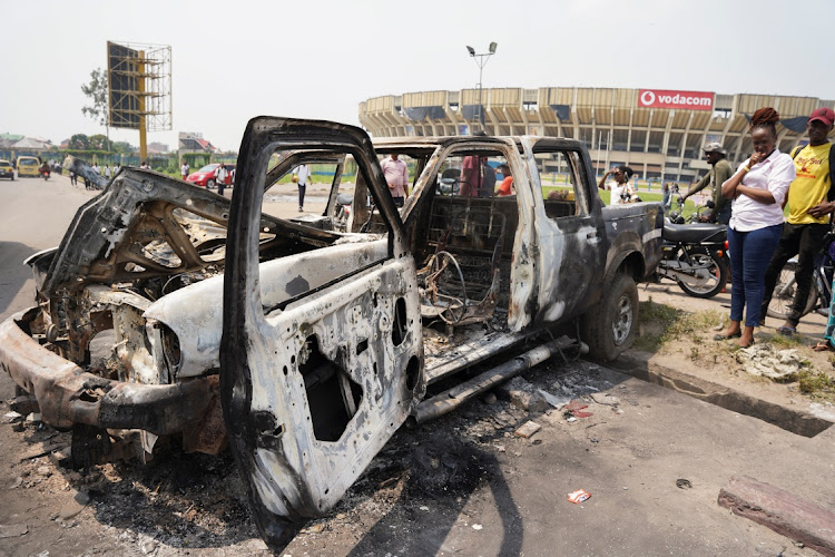 People inspect a burned police car, after two groups of Muslims clashed outside Martyrs Stadium in Kinshasa, Democratic Republic of Congo May 13, 2021.