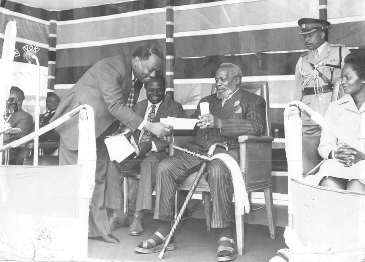 Mzee Jomo Kenyatta receiving cheques from S.M Githunguri on 15-12-1977