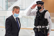 Former French President Nicolas Sarkozy, wearing a protective face mask, leaves after the verdict in his trial on charges of corruption and influence peddling at a Paris courthouse on March 1 2021. 