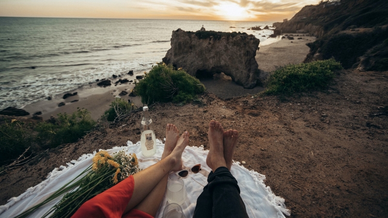 A couple sits on a blanket enjoying the view at El Matador Beach in Malibu, CA.