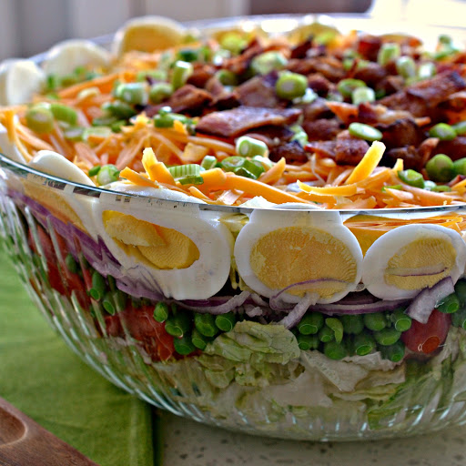 This tasty Seven Layer Salad is a real crowd please with sun ripened tomatoes, sweet peas, hard boiled eggs, crisp bacon and sharp cheddar. 