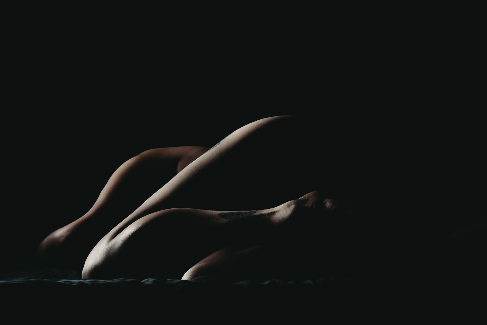 A bodyscapes image of a woman laying down on her side. You can see the curves of her legs, shoulder, and hips in the light. Photo by Embodied Art Boudoir. Classic boudoir photography, classic photography, classic boudoir, classy boudoir, classy photography, colorado boudoir, denver boudoir, boulder boudoir, colorado springs boudoir, boudoir ideas, boudoir poses, boudoir inspiration, photography inspiration, boudoir session, boudoir photos