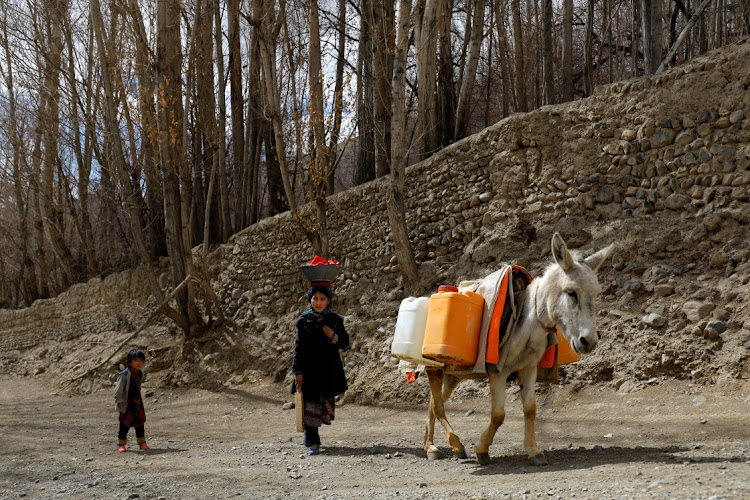 Children walk beside a donkey carrying water in Bamiyan, Afghanistan, on March 2 2023.