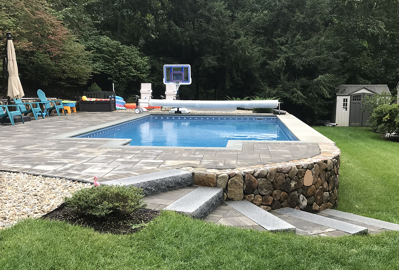 a semi-inground swimming pool with rock siding in a slope