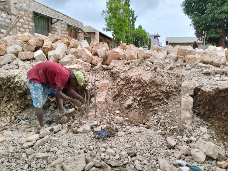 A fundi cuts metal from a house that had been constructed at Maganda settlement scheme.