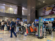 Passengers queue to check in for a flight on Singapore Airlines at O.R. Tambo International Airport in Johannesburg, South Africa, November 26 2021. 