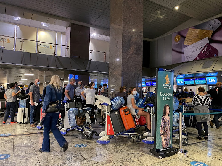 Passengers queue to check in for a flight on Singapore Airlines at O.R. Tambo International Airport in Johannesburg, South Africa, November 26 2021.