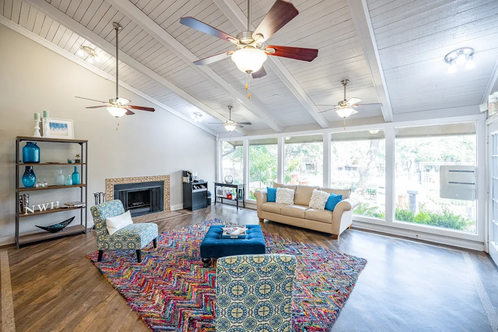 Clubhouse with wall-to-wall windows, wood plank flooring, couch, ottoman, chair, and fireplace