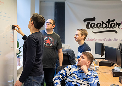 Four men are writing on a whiteboard in front of the Teester company sign.