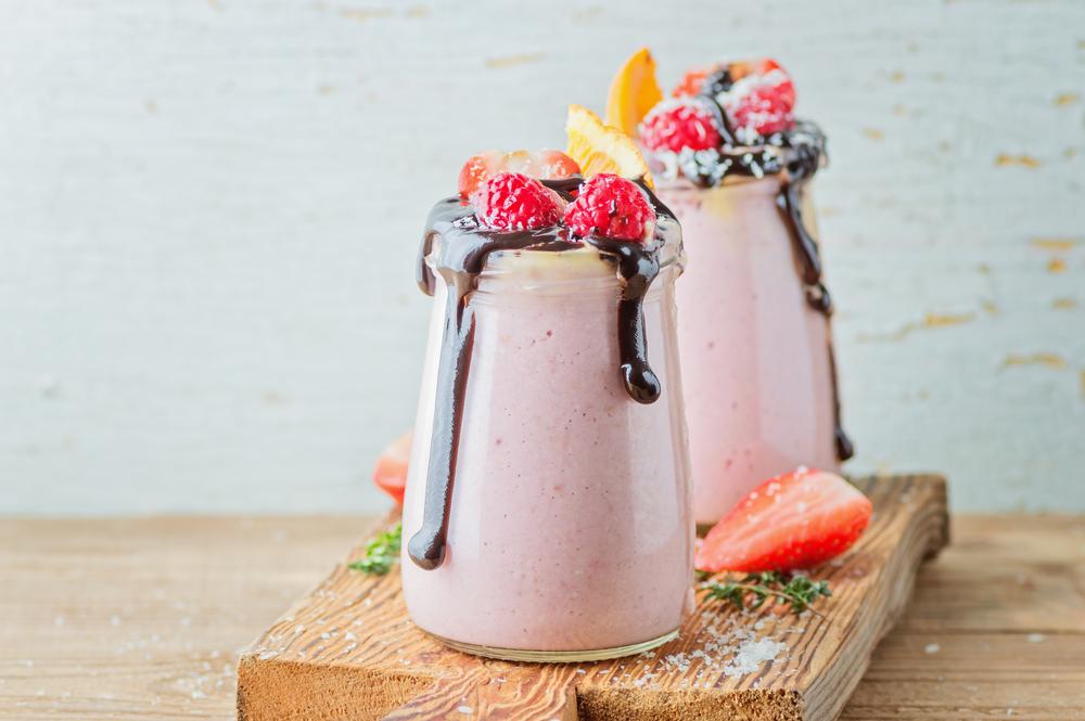 orange-strawberry smoothie with raspberries, yogurt and chocolate syrup. copy space
