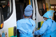 Medical staff at the Covid-19 facility at Chris Hani Baragwanath Hospital in Soweto assist a patient out of an ambulance to be admitted for treatment.