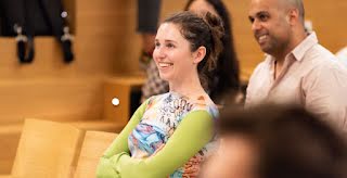 Couple of men and women are looking at something while smiling; One woman in focus.