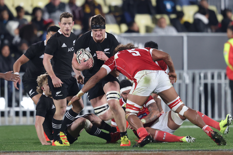 Scott Barrett of New Zealand (C) is tackled during the rugby Test match between the New Zealand All Blacks and Tonga in Auckland on July 3.