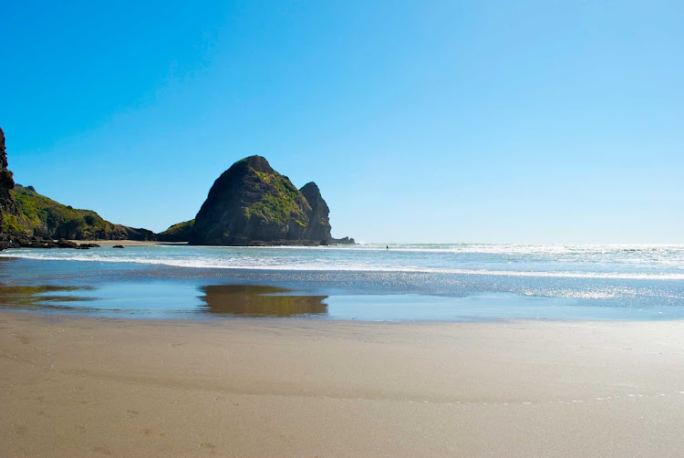 A view of Pina Beach in Auckland with a surfer in the distance. 