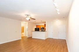 Corner of living room with a view of the kitchen ahead to the left and front door on the right