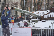 A man takes a picture of the destroyed Russian T-72B tank, secured from the Ukrainian village of Dmytrivka, outside Kyiv, on display in front of the Russian embassy in Riga, Latvia.