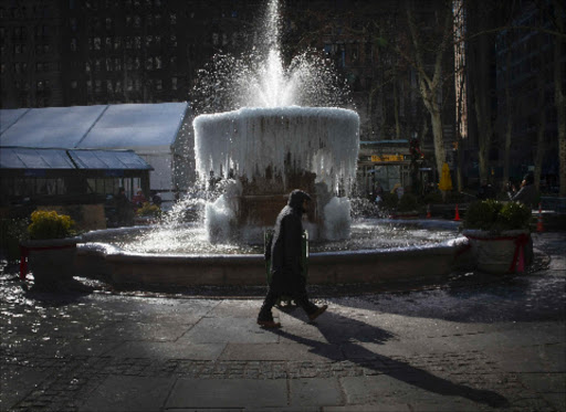 A man walks past the ice-covered Josephine Shaw Lowell Memorial Fountain, in frigid temperatures in Bryant Park in the Manhattan borough of New York City January 8, 2015