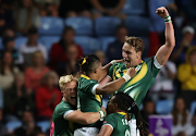 SA's Dewald Human and James Murphy celebrate with teammates after winning the Commonwealth Games rugby sevens gold on Sunday night. 