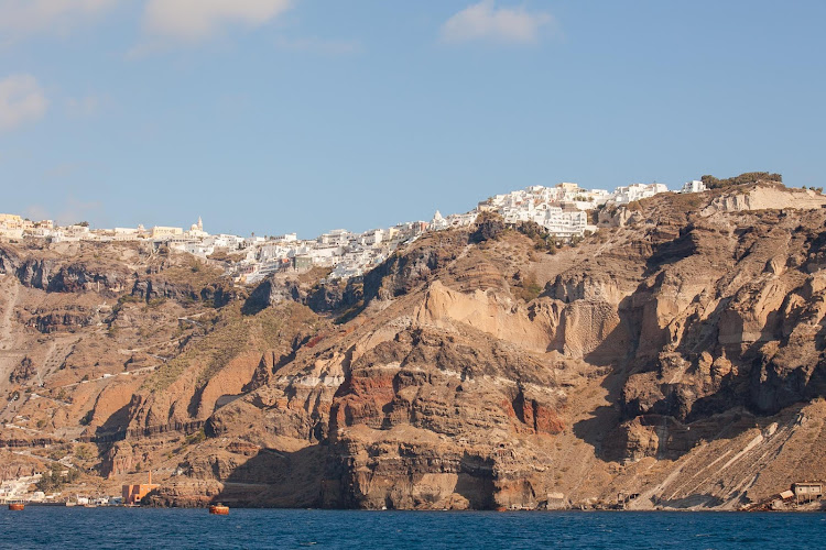 Whitewashed buildings line the rim of the caldera overlooking the Aegean Sea on Santorini, Greece. 