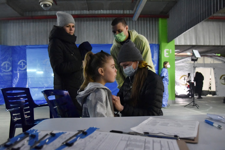 A child receives medical attention at a field hospital deployed by American doctors from the “Samaritan's Purse” organization in an underground parking lot of the King Cross Leopolis shopping mall, amid Russia's invasion of Ukraine, at the village of Sokilnyky, near Lviv, Ukraine on March 14 2022. Picture: REUTERS/PAVLO PALAMARCHUK