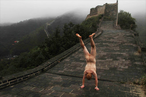 An anonymous man is doing handstands all over the world.