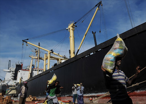 Somalian porters offload goods on April 24, 2013 in the sea port in Mogadishu from a foreign vessel like many of which have been captured along with their crews in the last five years by sea-going Somali pirates for ransom.