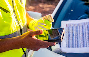 A traffic officer checks the validty of a motorist's drivers license at a roadblock.