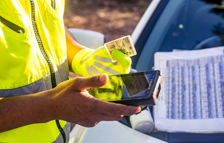 A traffic officer checks the validty of a motorist's drivers license at a roadblock.