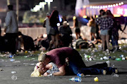 A man lies on top of a woman as others flee the Route 91 Harvest country music festival grounds after a gunman opened fire on the music festival in Las Vegas, killing 59 people. The shooter was later shot by police. The photographer witnessed the man help the woman up and they walked away. 