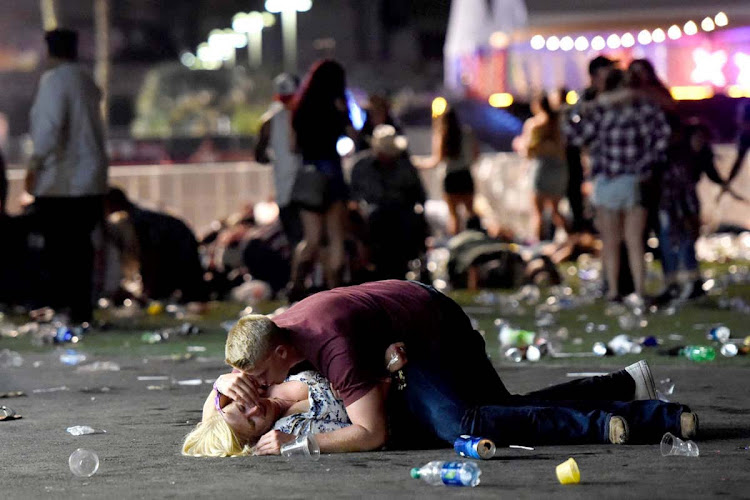 A man lies on top of a woman as others flee the Route 91 Harvest country music festival grounds after a gunman opened fire on the music festival in Las Vegas, killing 59 people. The shooter was later shot by police. The photographer witnessed the man help the woman up and they walked away.