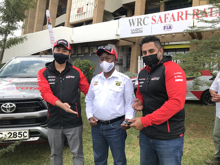 Toyota Kenya Sales coordinator Ryo Hasegama (L), sales and product trainer Sukhju Singh Kular (R) presents car keys of the 2021 Toyota Hilux GD series cars to WRC Safari Rally CEO Phineas Kimathi.