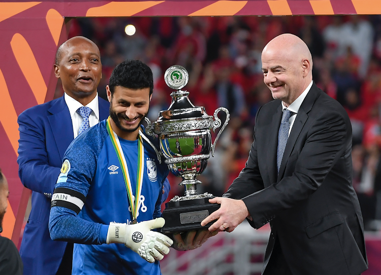 Fifa President Gianni Infantino (R) presents the winner's trophy to Al Ahly's goalkeeper Mohamed el-Shenawy (C) after the Confederation of African Football (CAF) Super Cup 2021 final match between Al Ahly of Egypt and Raja Casablanca of Morocco at the Ahmed bin Ali Stadium in Al-Rayyan, Qatar on December 22, 2021.