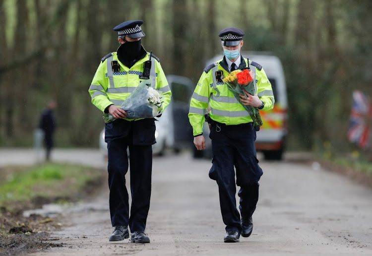 Police officers bring flowers at the golf course entrance, as the investigation into the disappearance of Sarah Everard continues, in Ashford, Britain, on March 11 2021.