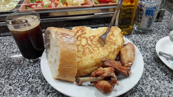 Tortilla de patatas, una de las especialidades de La Pomarada, acompañada de alitas