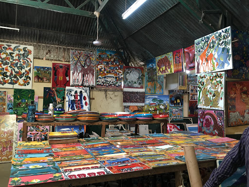 A table and walls covered in Tanzanian paintings