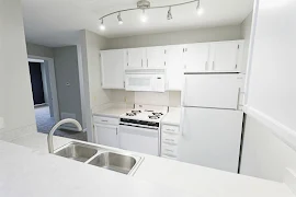 Kitchen with wood-inspired flooring, white appliances, and white cabinets