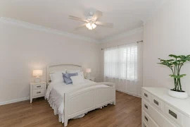 Bedroom with ceiling fan, tan walls, and wood-inspired flooring