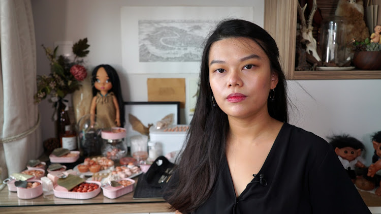 MACABRE MINIATURES: Singapore artist Qixuan Lim poses next to cans containing tiny cherubic fetus heads, arms and legs or other human body parts, which she sculpted using clay and cosmetic paint