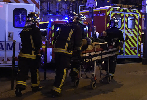 Rescuers workers evacuate a man on a stretcher near the Bataclan concert hall in central Paris, on November 13, 2015. AFP PHOTO / DOMINIQUE FAGET