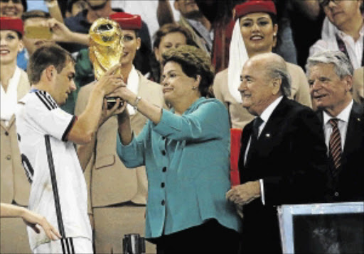 DELIGHT: Brazil's President Dilma Rousseff hands Philipp Lahm the World Cup trophy at the Maracana Stadium in Rio on Sunday as Fifa President Sepp Blatter, second right, and German president Joachim Gauck , right, look on PHOTO: Kai Pfaffenbach/REUTERS