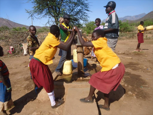 Primary school pupils pumping water from a borehole.