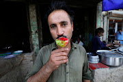 A man poses for a photo as he eats gola ganda, a shaved ice dessert, to cool off outside a cafe in Jacobabad, Pakistan, May 16, 2022. Jacobabad's roughly 200,000 residents are well aware of their reputation as one of the world's hottest cities. 