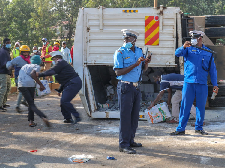 Police take control and disperse looting crowds at an accident scene involving a lorry ferrying cooking flour and two other saloon cars