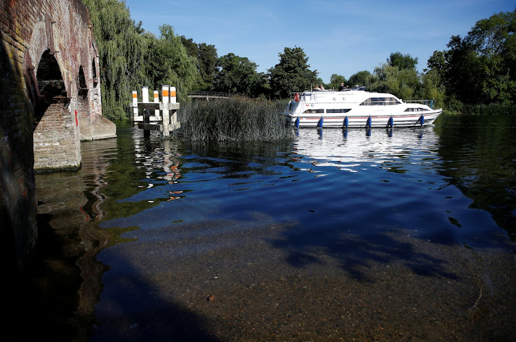 A boat passes under a bridge where water levels are low on the River Thames in Sonning, Britain, August 10, 2022.