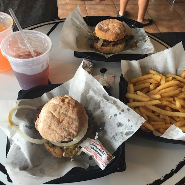 Front to back: baa burger with feta & onion on an onion bun. Garlic fries. Steak burger on original bun. Also pictured orange cream soda and black cherry soda.