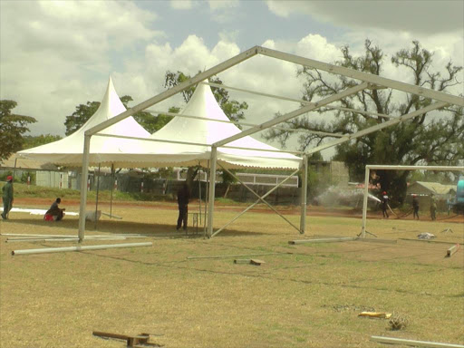 PREPARATIONS: Workers erect tents as a bowser pours water at Nanyuki Stadium yesterday. A large crowd is expected at the event to honour Devolution CS Mwangi Kiunjuri today. Photo/Eliud Waithaka